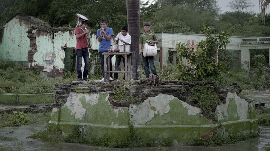 Fotograma de Los reyes del pueblo que no existe — banda tocando entre las ruinas